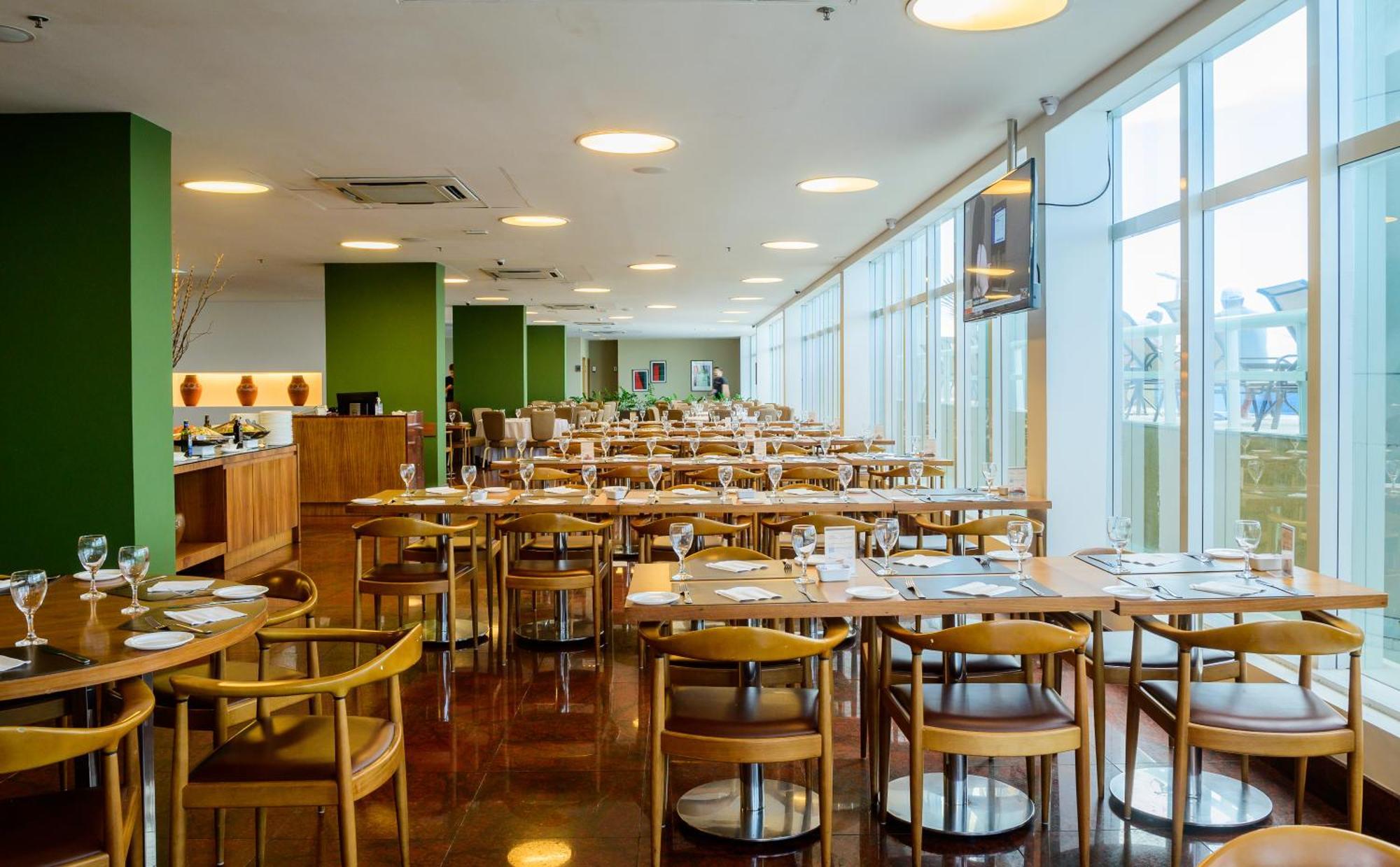 Hotel Luzeiros Sao Luis Extérieur photo The photo shows a spacious restaurant interior. It features rows of wooden tables and chairs arranged neatly, creating an inviting atmosphere. The walls are painted in a light color, accented by green, which adds a touch of freshness to the space. La