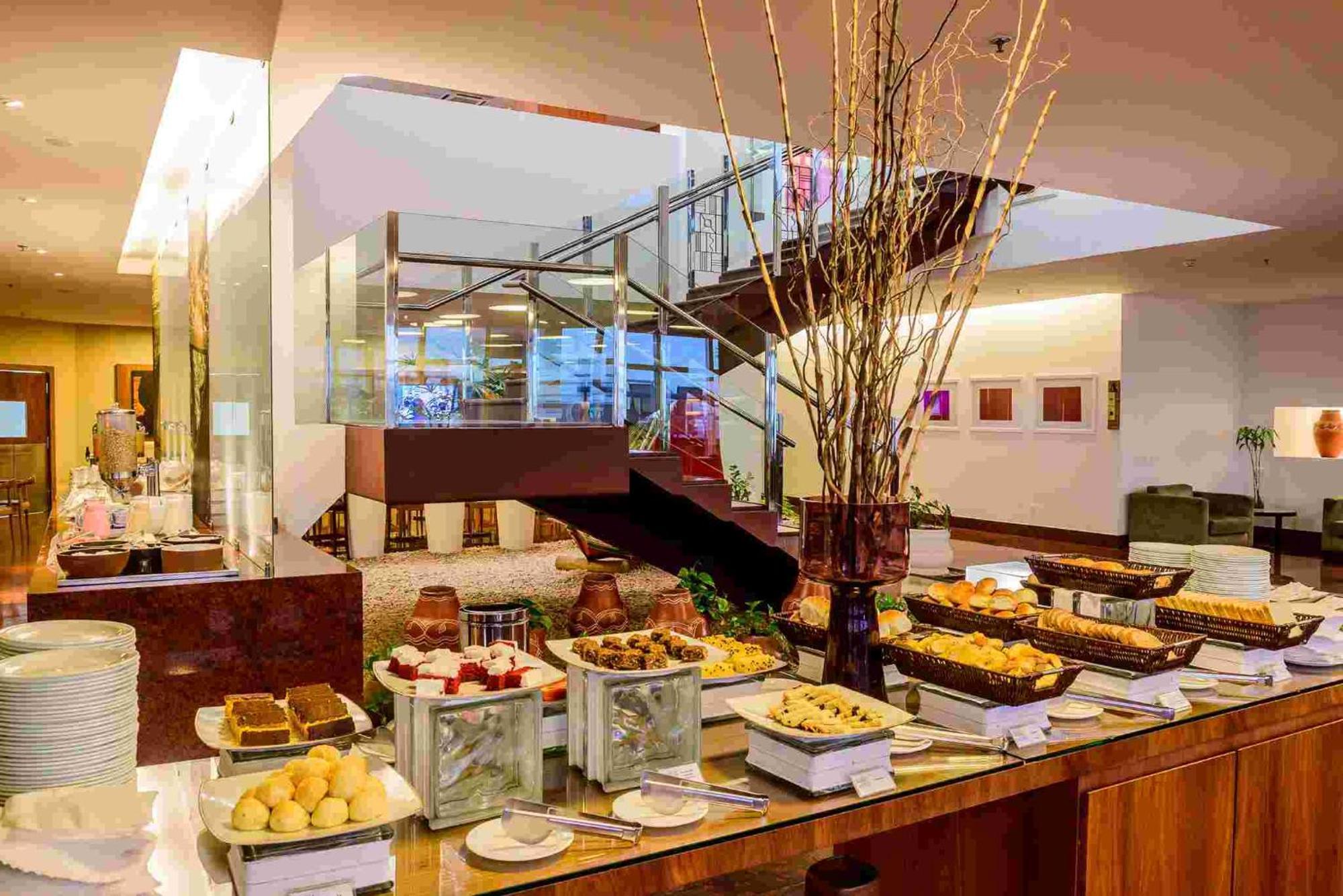 Hotel Luzeiros Sao Luis Extérieur photo The photo depicts an elegantly arranged dining area featuring a buffet setup. There are various food items displayed on long tables, including an assortment of pastries, desserts, and fruit. Decorative elements, such as tall branches in vases, add to