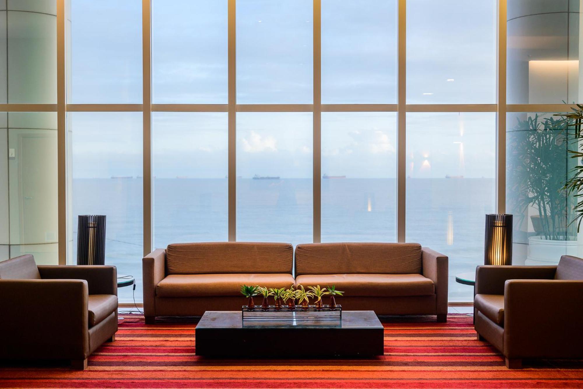 Hotel Luzeiros Sao Luis Extérieur photo The photo shows a modern lounge area with large windows overlooking a body of water. There are two brown sofas facing each other, accompanied by matching armchairs on either side. A coffee table, likely made of dark wood or stone, sits in the center 