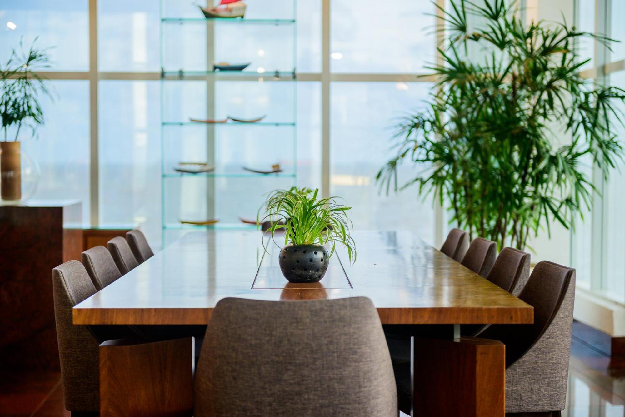 Hotel Luzeiros Sao Luis Extérieur photo The photo shows a modern dining area featuring a long wooden table surrounded by upholstered chairs. In the center of the table, there is a small potted plant. Behind the table, large windows allow natural light to fill the space, and there are shelv