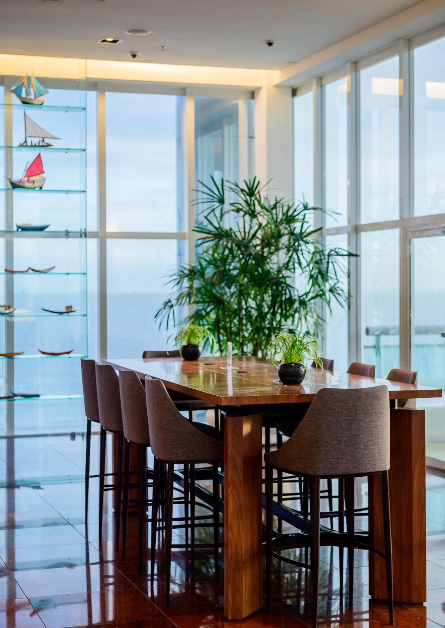 Hotel Luzeiros Sao Luis Extérieur photo The photo displays a dining area characterized by a large wooden table surrounded by several chairs. In the center of the table, there are small potted plants. Behind the table, there is a tall indoor plant that adds greenery to the space. 

To the s
