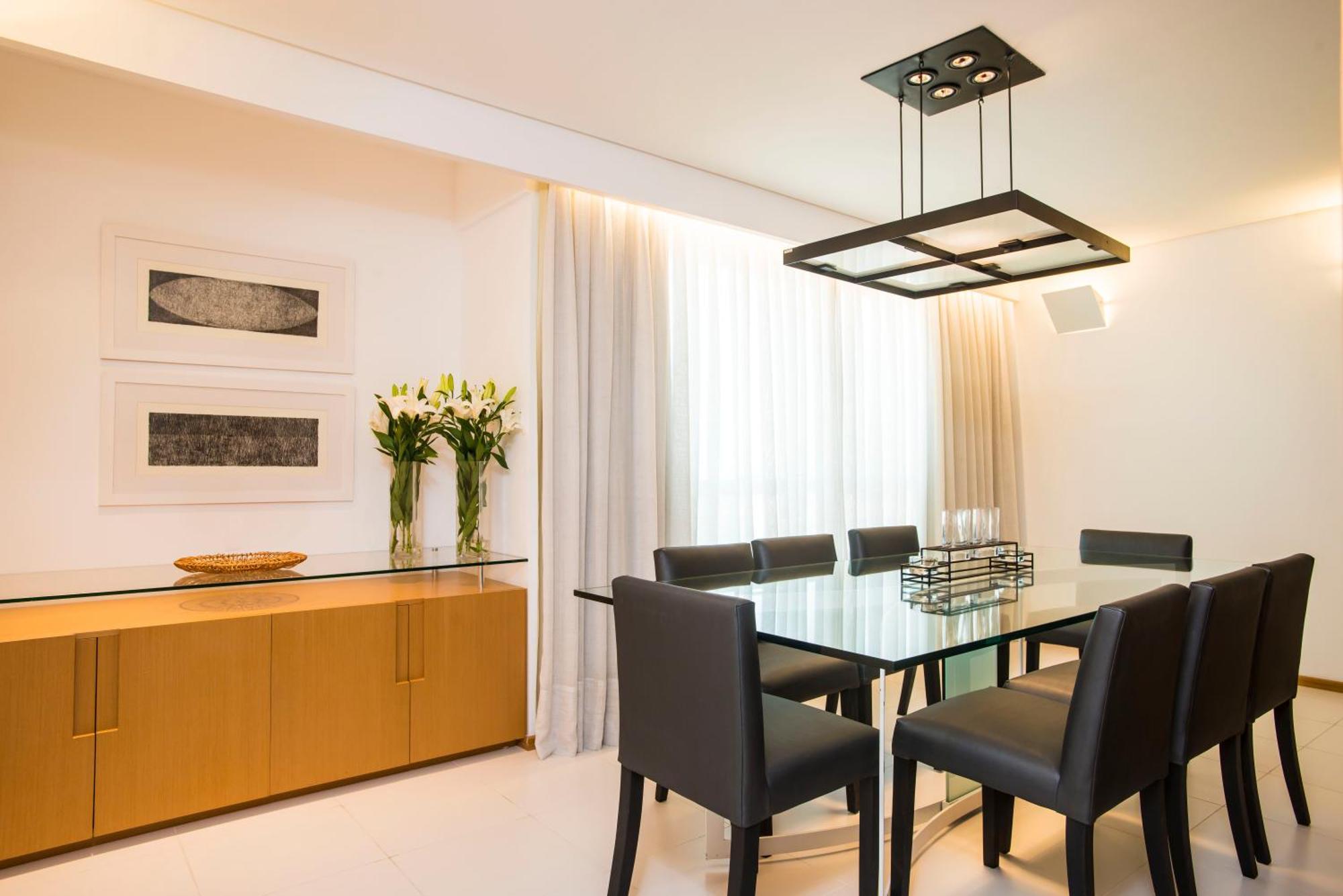Hotel Luzeiros Sao Luis Chambre photo The photo shows a modern dining room with a sleek design. In the center, there is a glass dining table surrounded by six black chairs. Above the table, there is a contemporary pendant light that has a square design. The walls are adorned with two abs