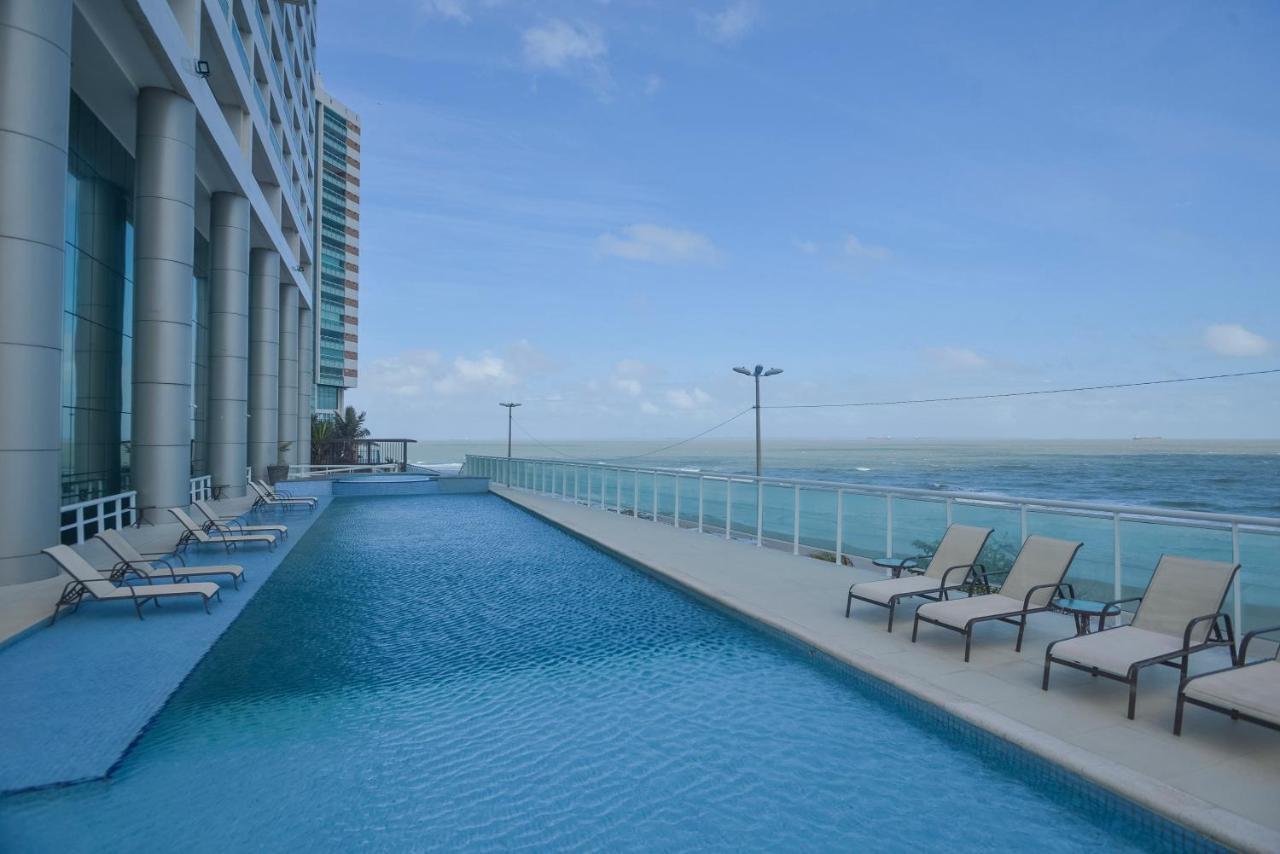 Hotel Luzeiros Sao Luis Extérieur photo The photo shows an outdoor swimming pool with a calm, blue water surface. The pool is surrounded by a deck, which includes several lounge chairs positioned along one side. In the background, there is a modern building, likely a hotel or resort, with 