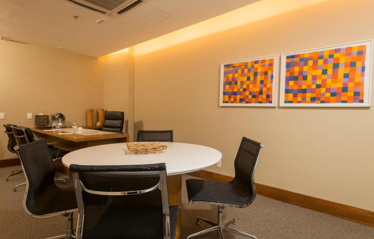 Hotel Luzeiros Sao Luis Extérieur photo The photo shows a stylish office or meeting room with a round white table in the center, surrounded by black chairs. The walls are neutral in color, and there are two pieces of abstract art hanging on the wall, featuring vibrant squares in hues of or