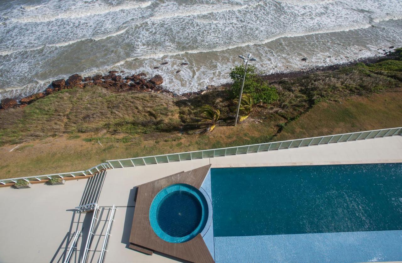 Hotel Luzeiros Sao Luis Extérieur photo The photo shows an aerial view of a swimming pool area next to a beach. The scene includes a larger pool with a smaller circular hot tub attached to it. The pool area is surrounded by a deck, and there are some lounge chairs visible. In the backgroun