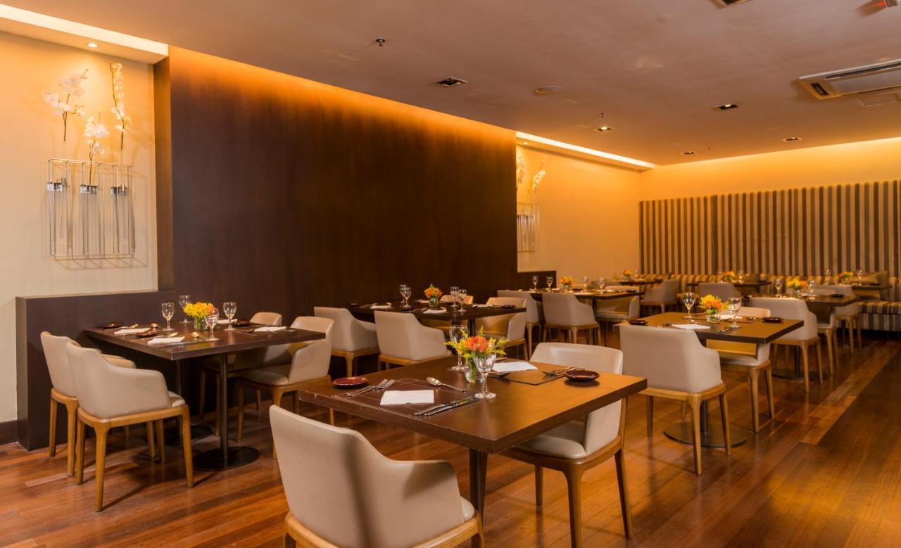 Hotel Luzeiros Sao Luis Extérieur photo The photo shows a modern restaurant interior. There are several tables arranged with light wooden surfaces and comfortable cream-colored chairs. Each table has a flower centerpiece and is set with tableware, including wine glasses and plates. The wal