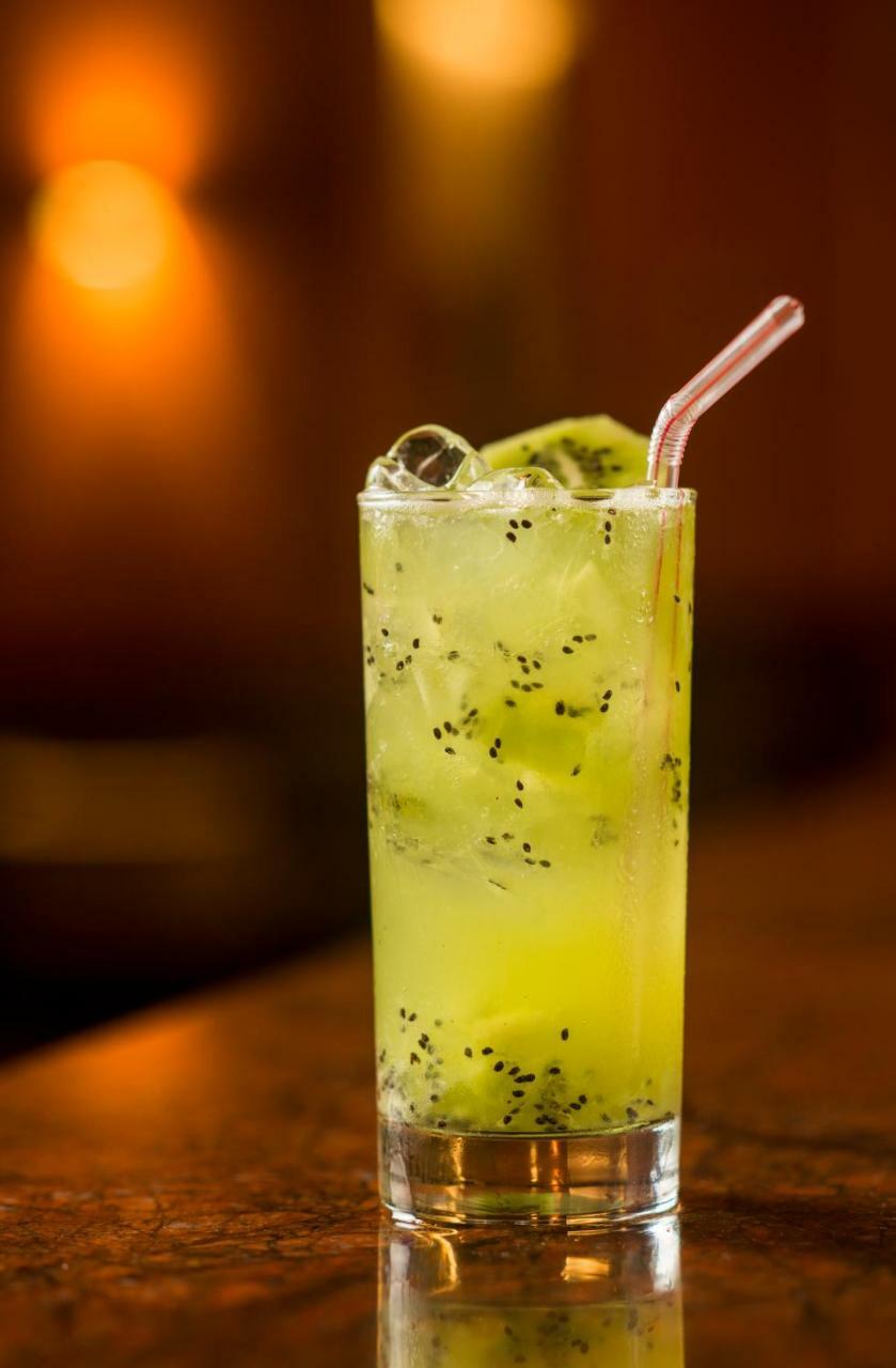 Hotel Luzeiros Sao Luis Extérieur photo The image features a tall glass filled with a refreshing, green beverage. The drink is a light, vibrant green color and contains ice cubes, adding to its chill appeal. Floating within the drink are small black seeds, likely from a fruit ingredient. A